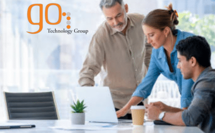 Three professionals discussing IT consulting strategy around a laptop in a modern Chicago office