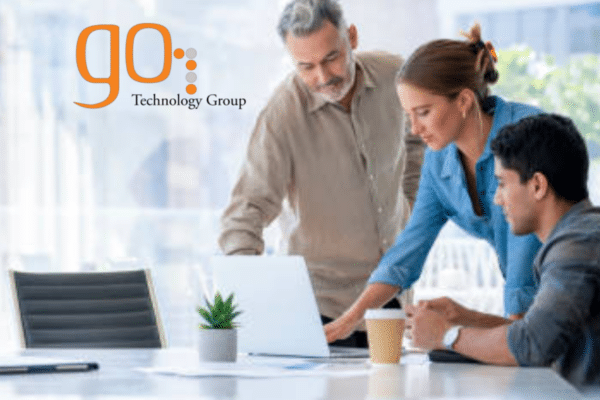 Three professionals discussing IT consulting strategy around a laptop in a modern Chicago office