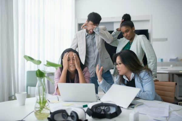 Frustrated team gathered around a laptop facing technology challenges before engaging IT consulting support