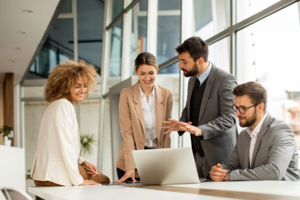 Business team discussing AI for business strategy around a laptop in a modern office setting