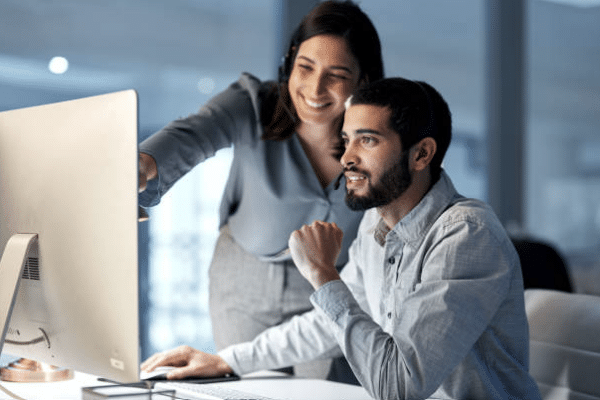 Two professionals reviewing business continuity strategies on a computer monitor at a managed IT workstation