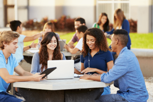 High school students collaborating around a laptop and tablet, representing AI in education solutions for schools in Chicago.