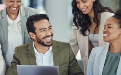 Diverse team of business professionals collaborating around a laptop in a modern office, representing data-driven teamwork and proactive IT strategies by a Chicago managed service provider.