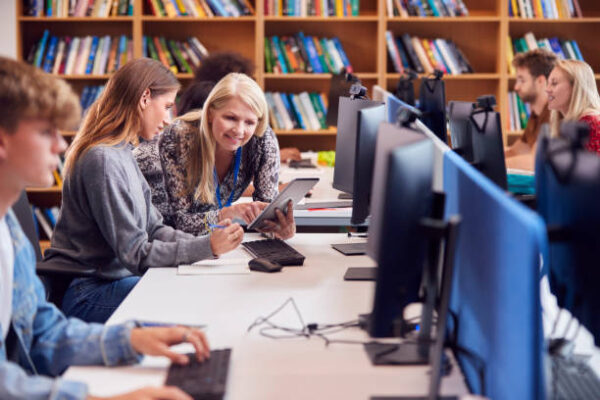 Library staff and students using shared computers as part of technology support for libraries