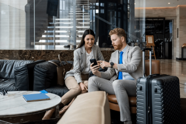 Business professionals reviewing information on a smartphone while traveling, illustrating cybersecurity considerations related to remote work and public connectivity.